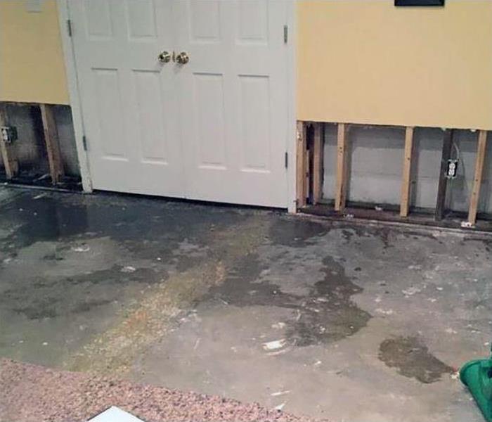 room with water damage on concrete floor and drywall removed from bottom 2 feet. 