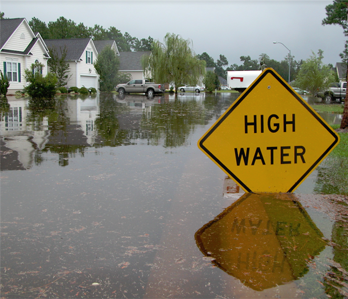 a sign that says high water and is partially submerged under flood water
