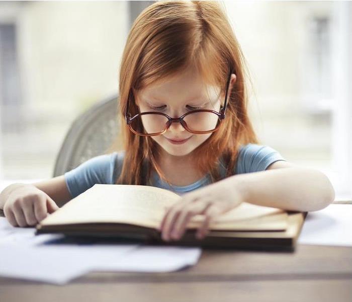 girl with oversized glasses reading book